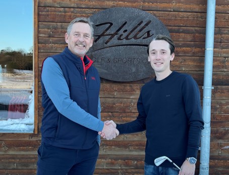 Två män skakar hand och ler in i kameran